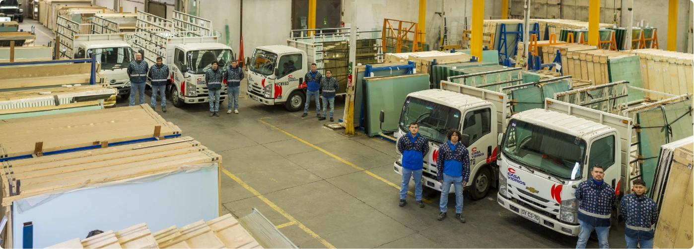 Equipo de Casa Vidrios junto a los camiones de despacho en la bodega